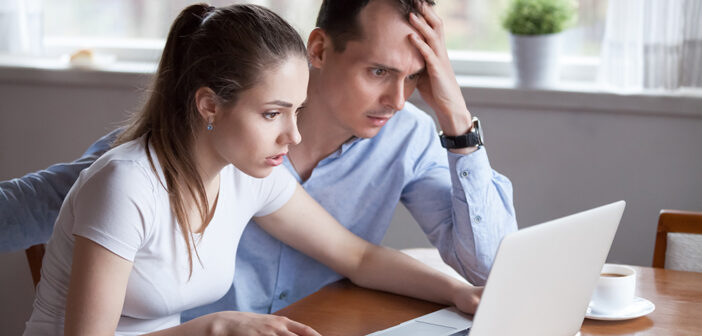 Investment Scams: What To Look Out For Couple looking worried and stressed whilst using laptop